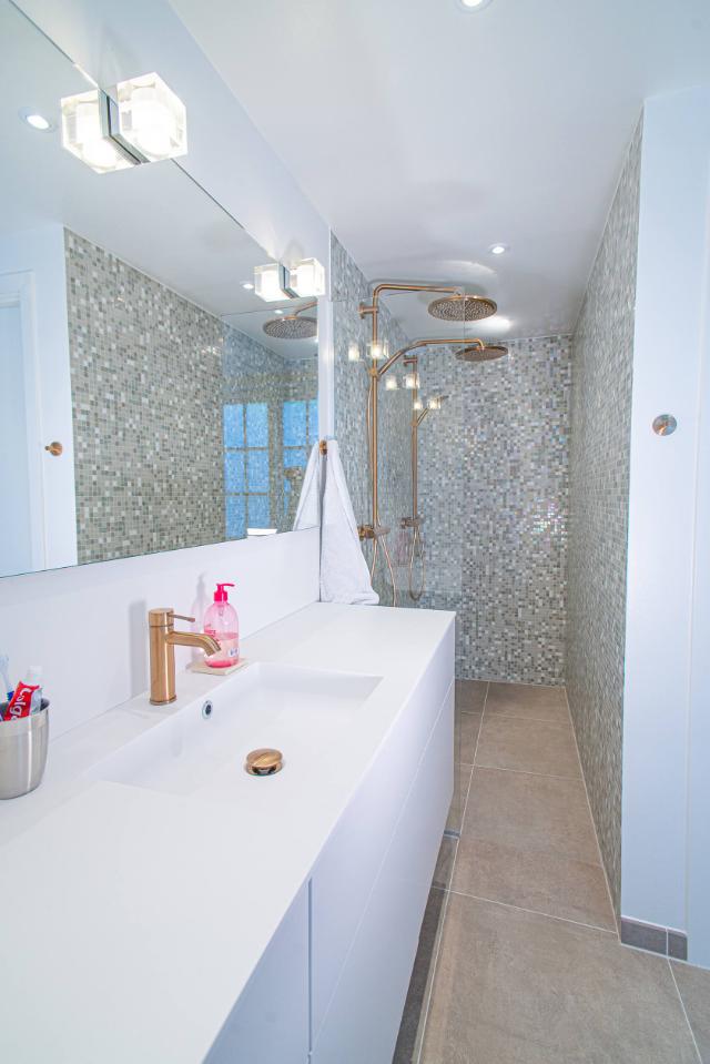 Unikt badeværelse med hvidt badeværelsesmøbel og vandhane i guld